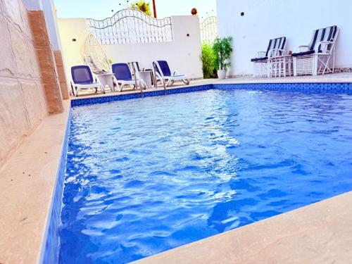 a swimming pool with blue chairs in a building at White Gorf Hotel in Luxor