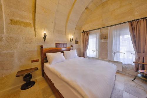 a bedroom with a large bed in a stone wall at Nora Cave Hotel in Goreme