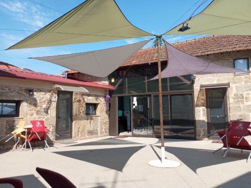 a large umbrella on a patio in front of a building at Albergue do Visconde in Touguinha