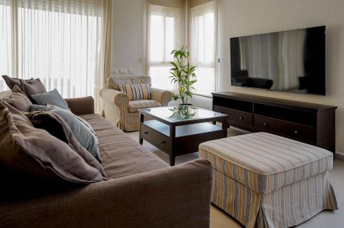 a living room with a couch and a tv at YalaRent Eilat Villa 4BR Private Pool & Garden in Eilat