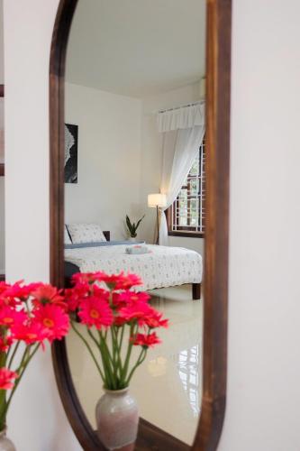 a mirror reflecting a bedroom with a bed and flowers at Green homestay, Huế in Hue