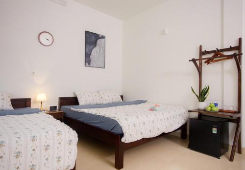 a bedroom with two beds and a clock on the wall at Green homestay, Huế in Hue