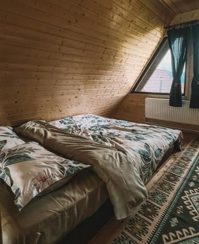 a bed in a wooden room with a window at Căbănuțele de lângă râu in Păucineşti