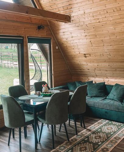 a living room with a table and chairs and a couch at Căbănuțele de lângă râu in Păucineşti