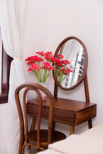 a mirror and a chair and a vase with flowers at Green homestay, Huế in Hue