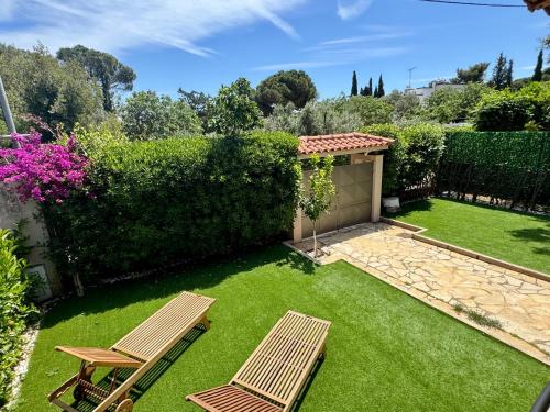 a garden with two chairs and a hedge at Nea Makri Holiday Villa in Nea Makri