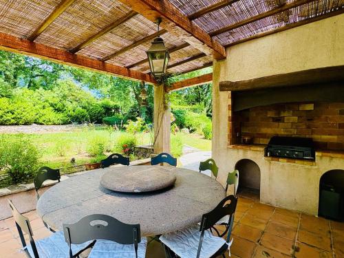 un patio avec une table, des chaises et une cheminée dans l'établissement Hacienda Provençale- Piscine, Pétanque et Plenitude, à Saint-Jeannet
