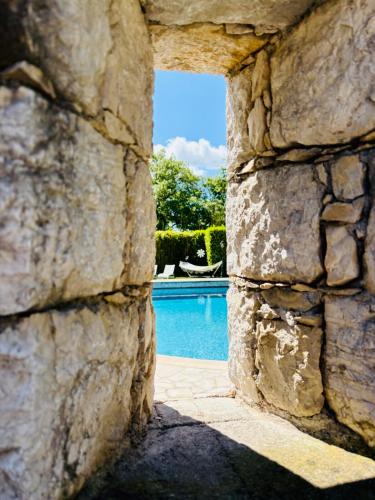 une vue d'une piscine à travers un mur de pierre dans l'établissement Hacienda Provençale- Piscine, Pétanque et Plenitude, à Saint-Jeannet
