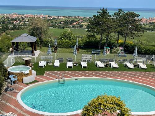 a large swimming pool with chairs and a gazebo at B&B Villa Alma in San Costanzo