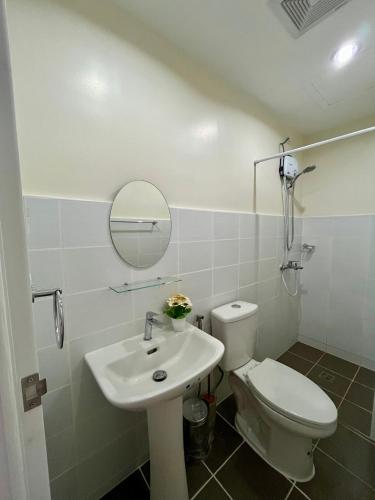 a bathroom with a sink and a toilet and a mirror at Raph Staycation near Mactan Newtown in Lapu Lapu City