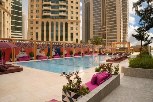 duży basen z różowymi poduszkami obok budynków w obiekcie Andaz Doha, by Hyatt w mieście Doha