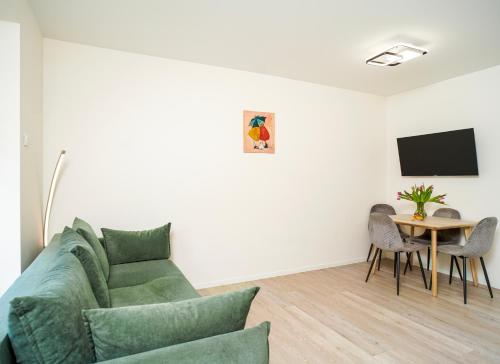 a living room with a green couch and a table at Apartamentai Saulėgrąža in Palanga
