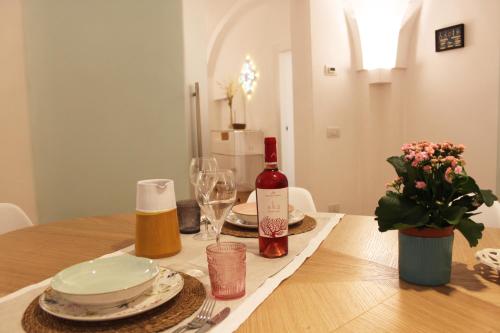 a dining room table with a bottle of wine and flowers at Ademè dimora di charme in Monopoli