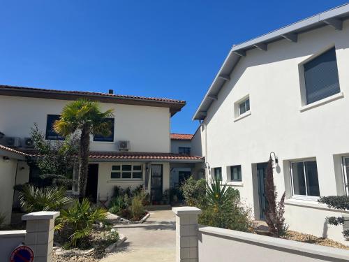 a white house with a palm tree in front of it at Hôtel La Pinède in Soulac-sur-Mer
