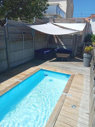 une piscine avec une terrasse en bois et un parasol dans l'établissement À 300m de la mer maison - jardin - Piscine pour 4, à Sainte-Marie
