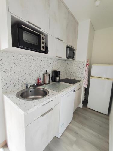 une cuisine avec un évier et un micro-ondes dans l'établissement Appartement avec grande terrasse au centre ville d'Uzès, à Uzès