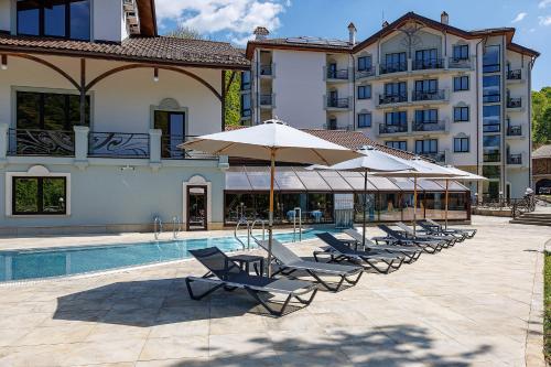 a group of chairs and umbrellas next to a pool at Molfar Resort Hotel & SPA Карпати in Shaian