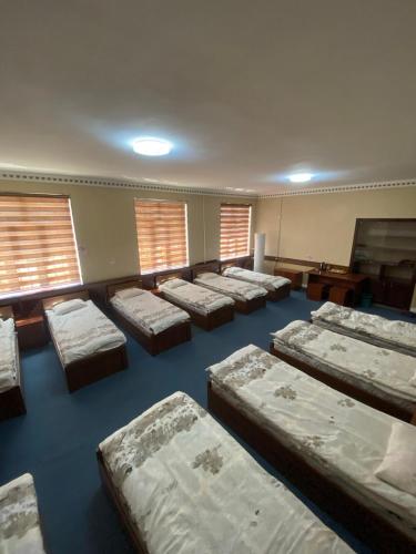 Zimmer mit einer Reihe von Betten in einem Zimmer mit Fenstern in der Unterkunft Hostel INN Andijan in Andizhan