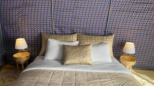 a bedroom with a bed with two lamps on it at Dar Tawarta Guest House Dakhla in Dakhla