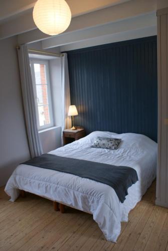 une chambre avec un grand lit avec un mur bleu dans l'établissement Le Clos des Capitaines, entre mer et campagne, à Montfarville