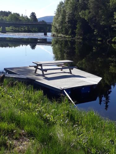 a picnic table sitting on a dock next to a lake at 16 - Fulufjellets nasjonalparker - snø - alpint - langrenn - snøscooter in Ljørdal