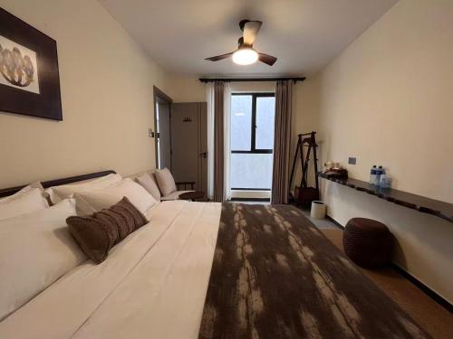 a bedroom with a large white bed with a ceiling fan at Yeza inn 悦在民宿 in Nairobi