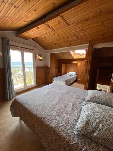 une chambre avec deux lits et une grande fenêtre dans l'établissement Le Surplage, à Hyères