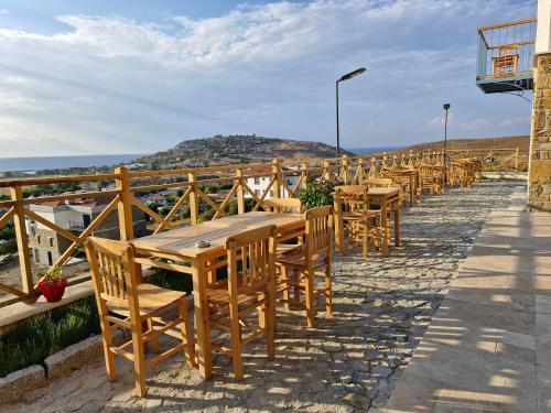 a row of wooden tables and chairs on a balcony at Fengari Ada Evi in Gökçeada