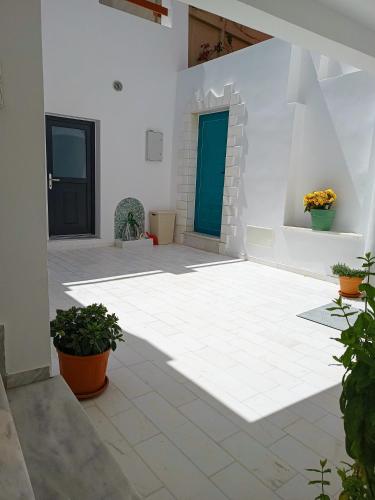 a white courtyard with two doors and plants at Blue Bergamote Syros in Ermoupoli