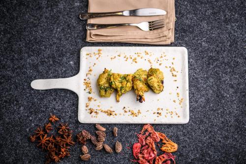a plate of food with broccoli on a table with nuts at Best Western Plus Revanta Mcleod Ganj in Dharamshala
