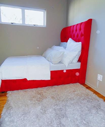 a bed with a red headboard in a bedroom at BKaap2 Queens and Kings Guest House in Cape Town