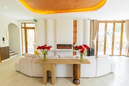 a living room with a couch and a table with flowers at Meraki Villa Đà Lạt in Khu Chi Lăng