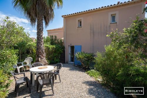 un patio avec des chaises et une table devant une maison dans l'établissement Spacieuse villa au cœur du Golf de Béziers, à Béziers