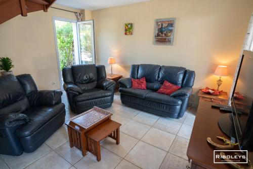 - un salon avec des canapés en cuir noir et des oreillers rouges dans l'établissement Spacieuse villa au cœur du Golf de Béziers, à Béziers