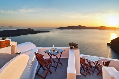 a table and chairs on a balcony with a view of the ocean at Smaro Studios in Firostefani