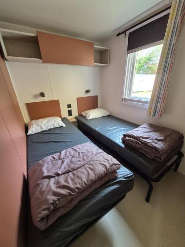 deux lits dans une petite pièce avec une fenêtre dans l'établissement Mobilhome 6 personnes domaine de la yole, à Vendres