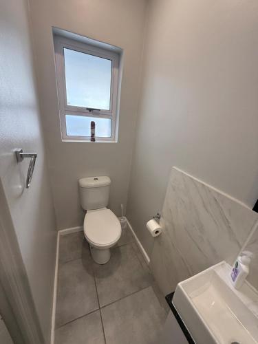 a white bathroom with a toilet and a window at Table Mountain View Apartment in Cape Town