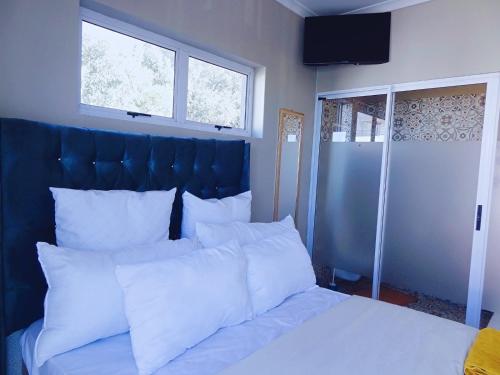 a bed with white pillows and a blue headboard at BKaap2 Queens and Kings Guest House in Cape Town