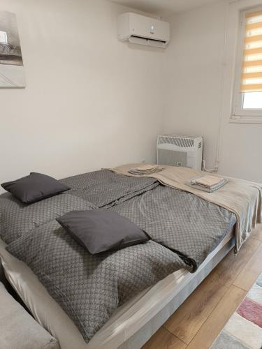 a white bedroom with a large bed with black pillows at Harka Central Apartman in Harkány