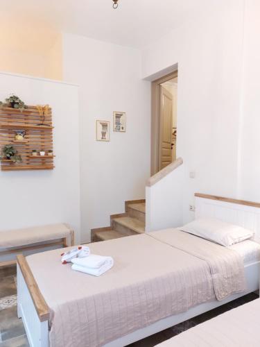 a white bedroom with a bed and a staircase at Iliaxtida Apartment in Agia Paraskevi