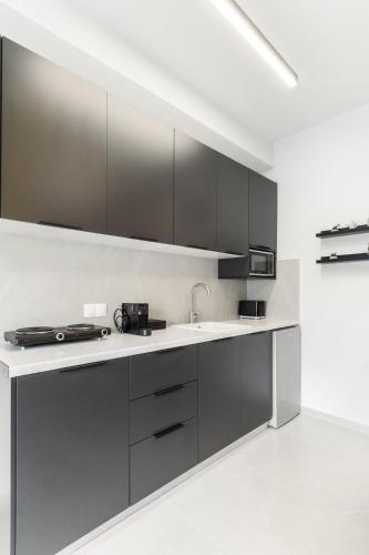 a kitchen with black cabinets and a sink at Loka Residence in Kavala