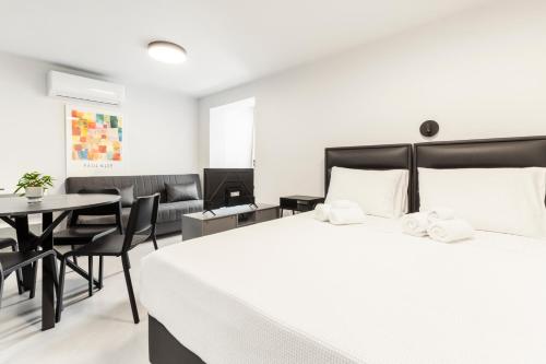 a bedroom with a large white bed and a table at Loka Residence in Kavala