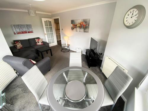 a living room with a table and a clock on the wall at NEW Super 2 Bedroom Flat in Falkirk in Falkirk