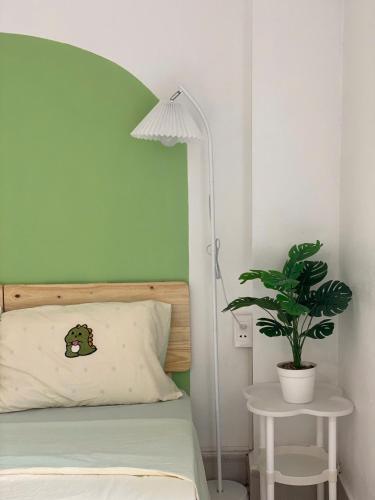 a bedroom with a bed with a green headboard and a plant at Full House Cát Bà in Cat Ba