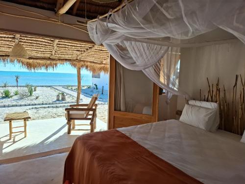 a bedroom with a bed and a view of the beach at Beheloka Lodge in Ambalaviro