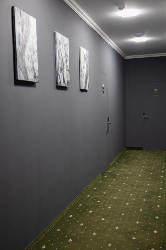 a room with three paintings on the wall and a green carpet at Colette Hotel in Yerevan