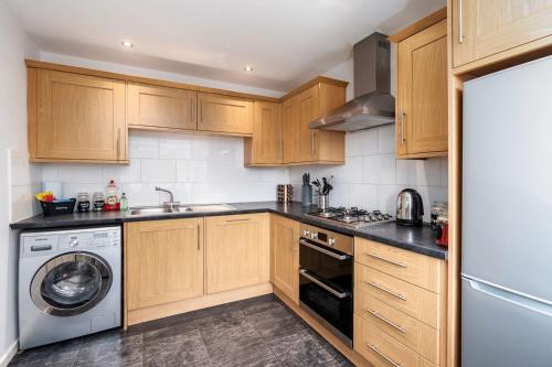 a kitchen with wooden cabinets and a washer and dryer at Stunning 3 Bedroom Home Hillsborough Sheffield in Sheffield