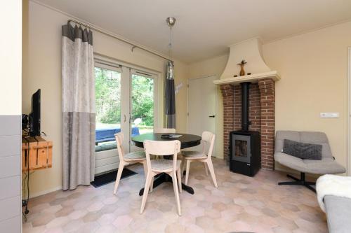 a living room with a table and chairs and a fireplace at Wina Boshuisje Veluwe in Otterlo
