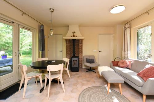 a living room with a couch and a table and chairs at Wina Boshuisje Veluwe in Otterlo