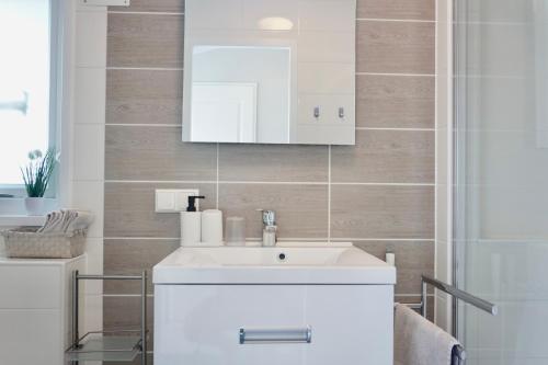 a bathroom with a white sink and a mirror at Ferienhaus Ufergeheimnis am Gülser Moselbogen I 2 SZ I 5 Gäste I Badebucht I Grill I Garten in Koblenz